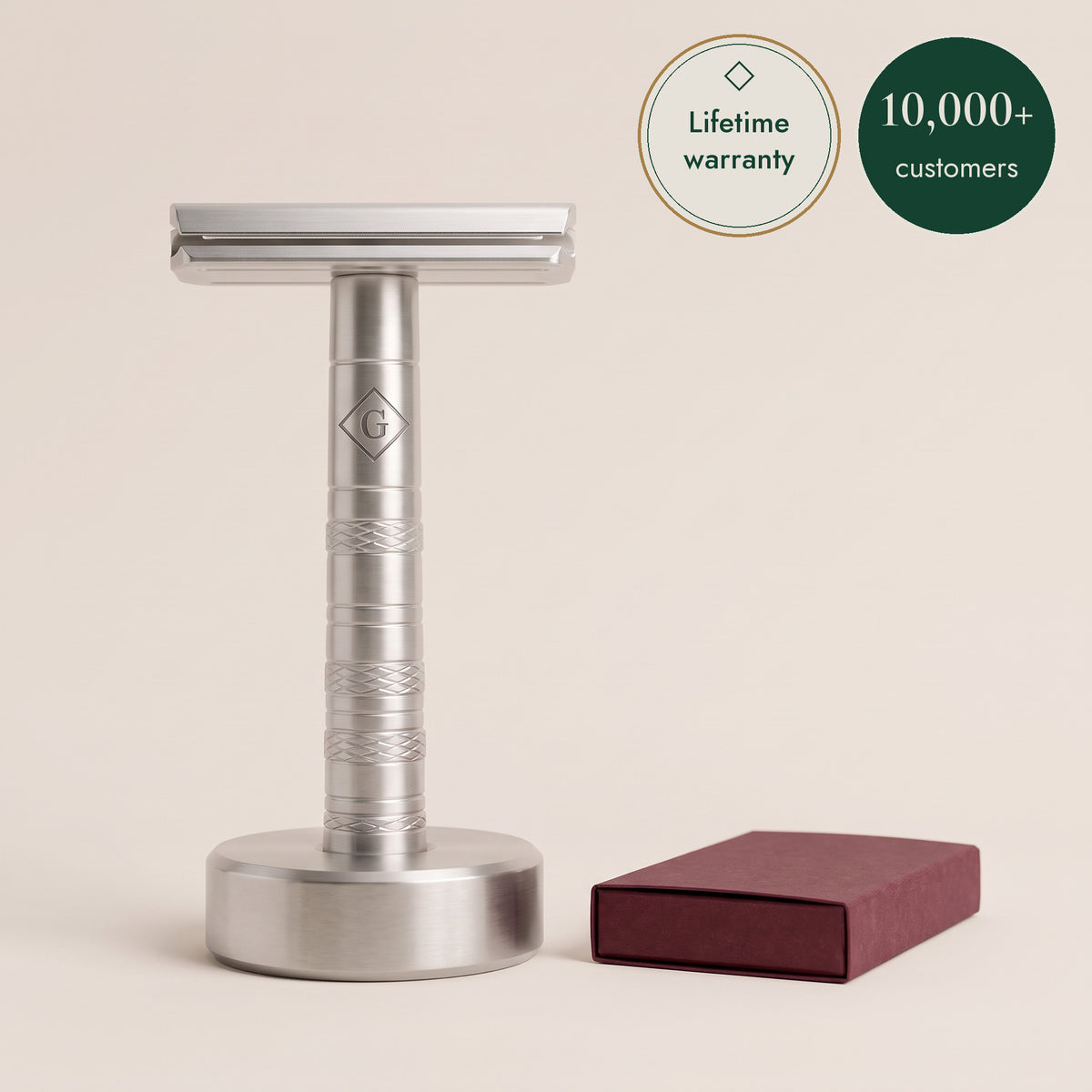 The Razor in brushed steel, upright on its weighted stand, with a box of ten blades