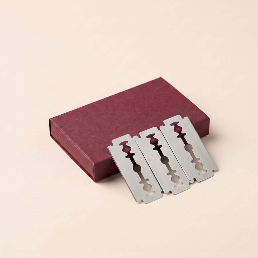 A burgundy box of ten standard double-edge razor blades, three blades beside it