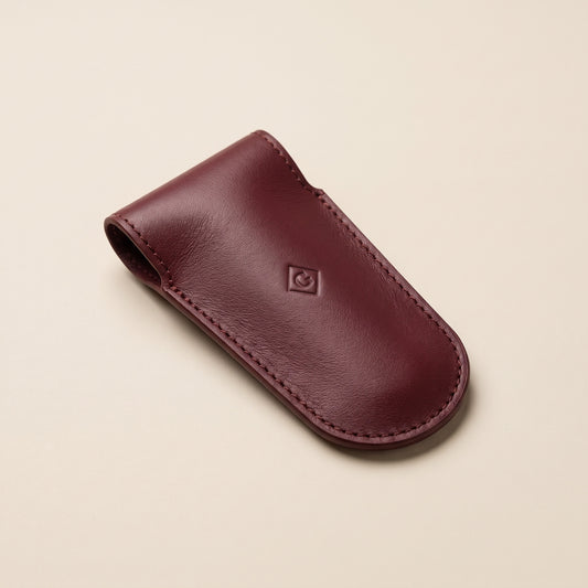 The burgundy leather sleeve for the razor head, with a small pressed G